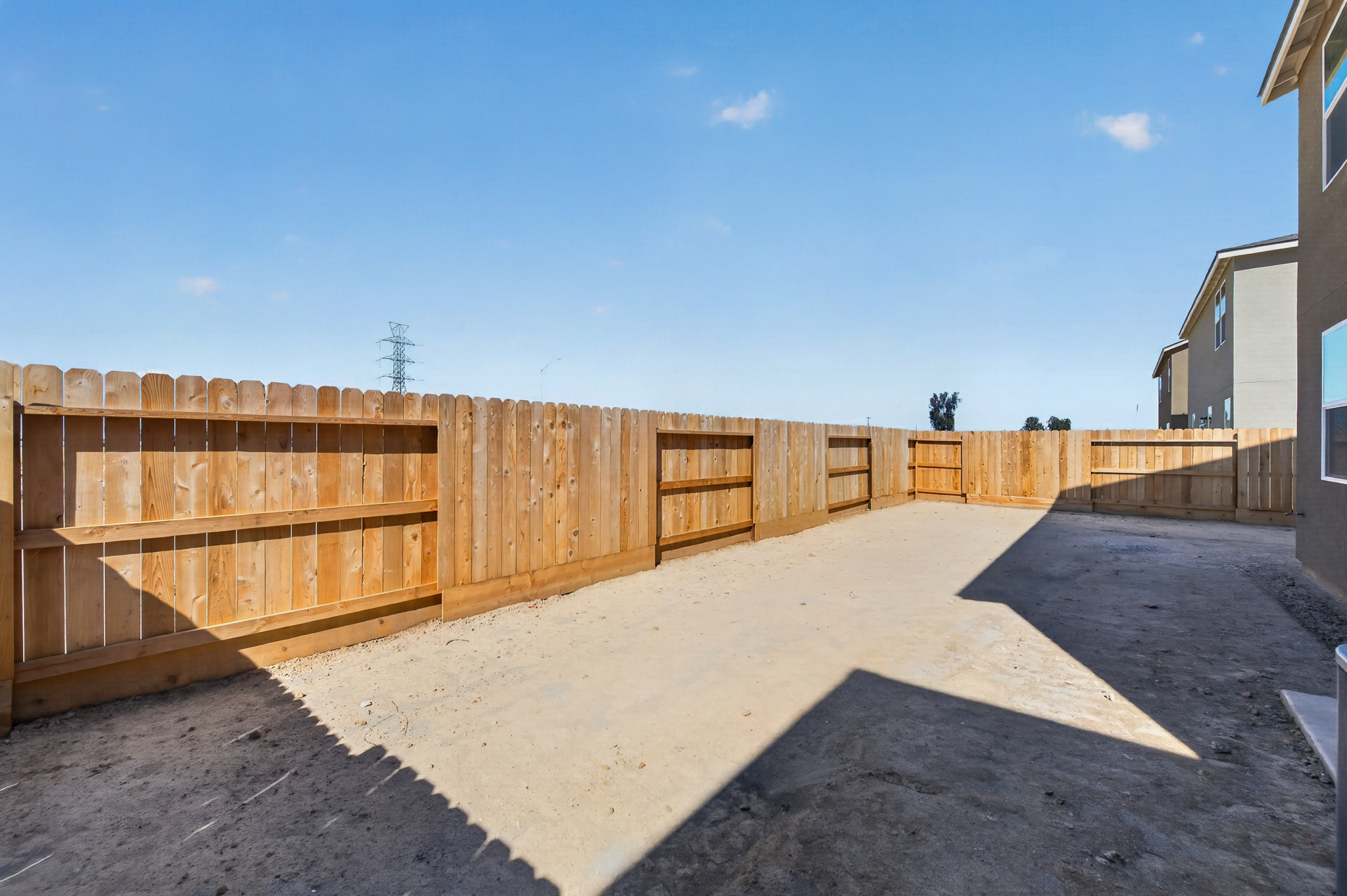 A fenced off area with a wood wall and a blue sky.
