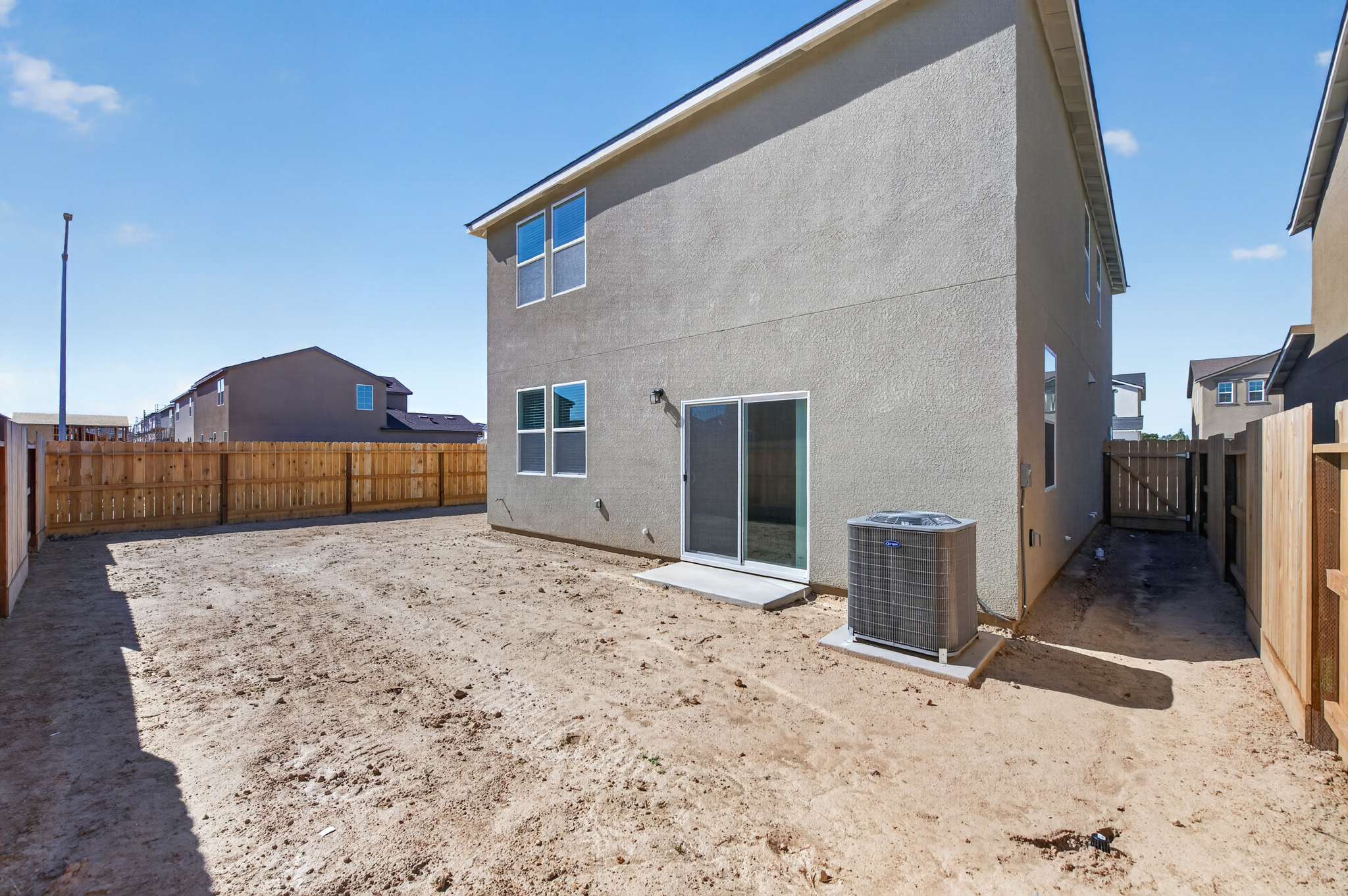 A house with a fence and dirt in front of it.