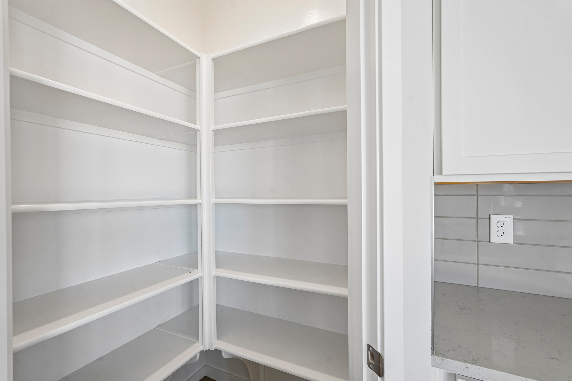 A white shelf with white cabinets.