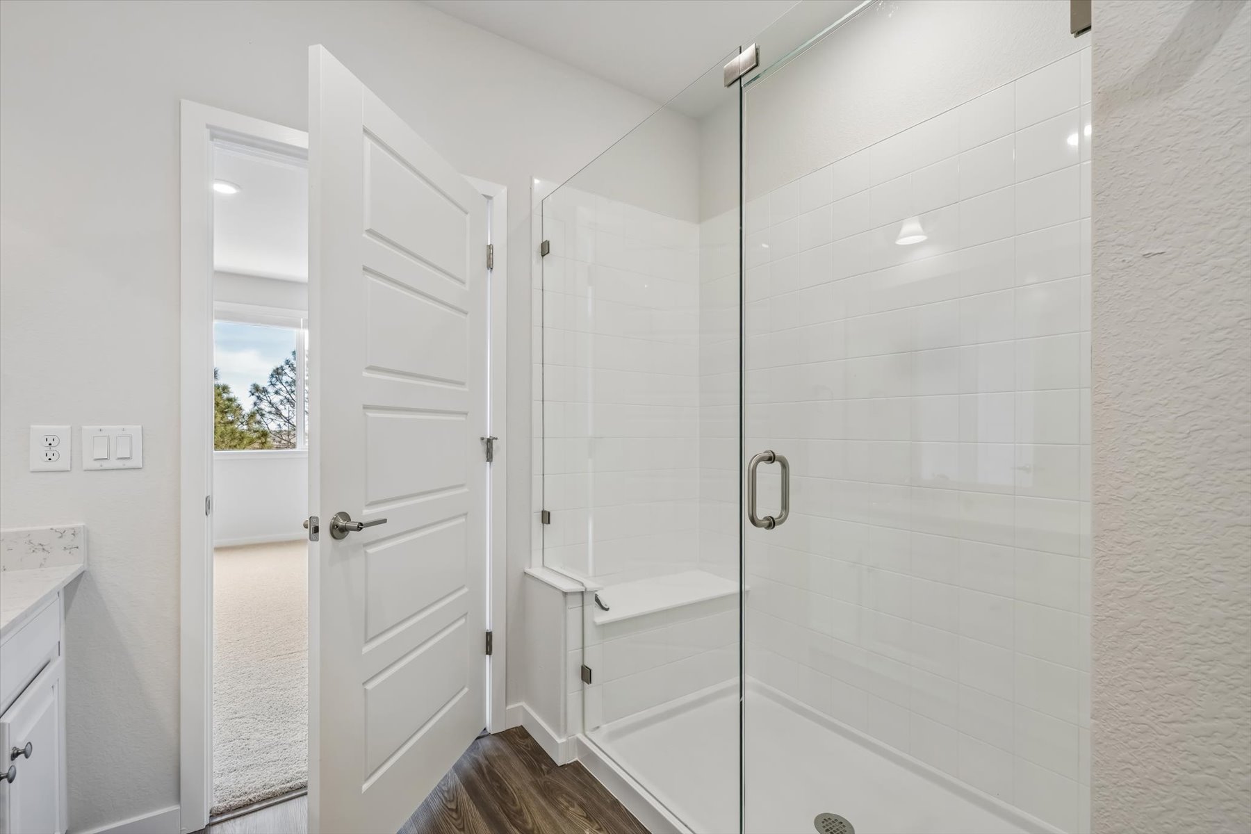 A bathroom with a shower unit and a glass door.