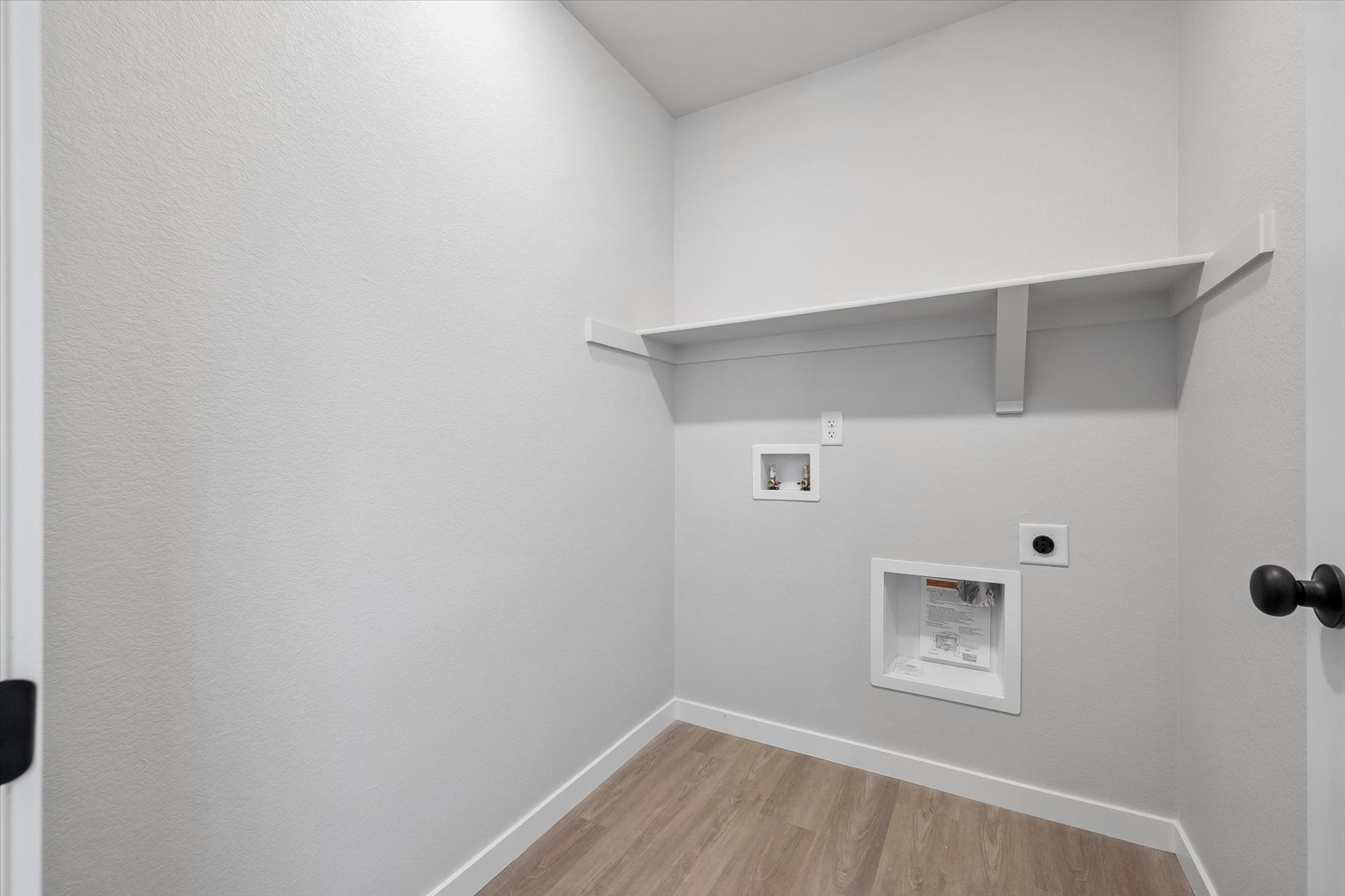 A white room with a wood floor and a white wall with a white shelf and a wood floor.