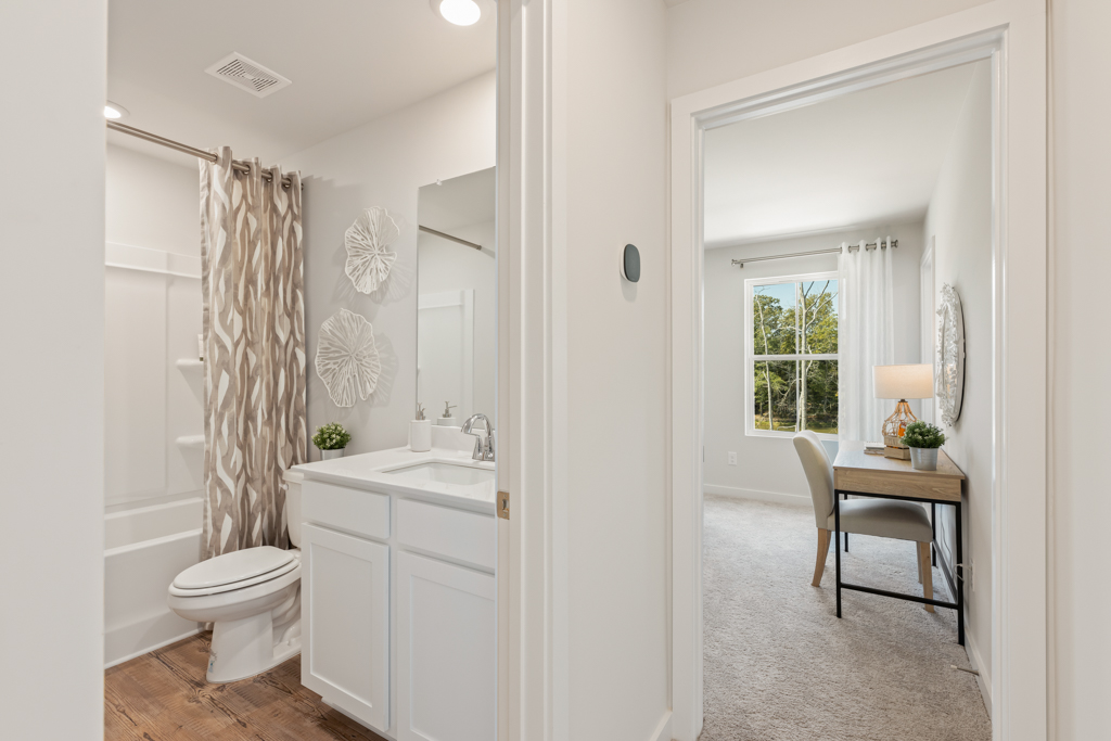 A bathroom with a sink toilet and a mirror.