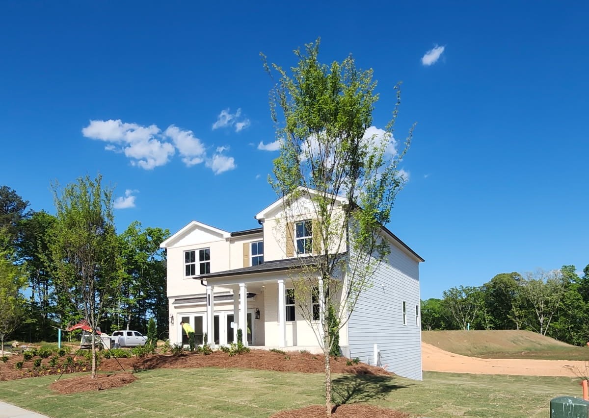 A white house with a tree in front of it.
