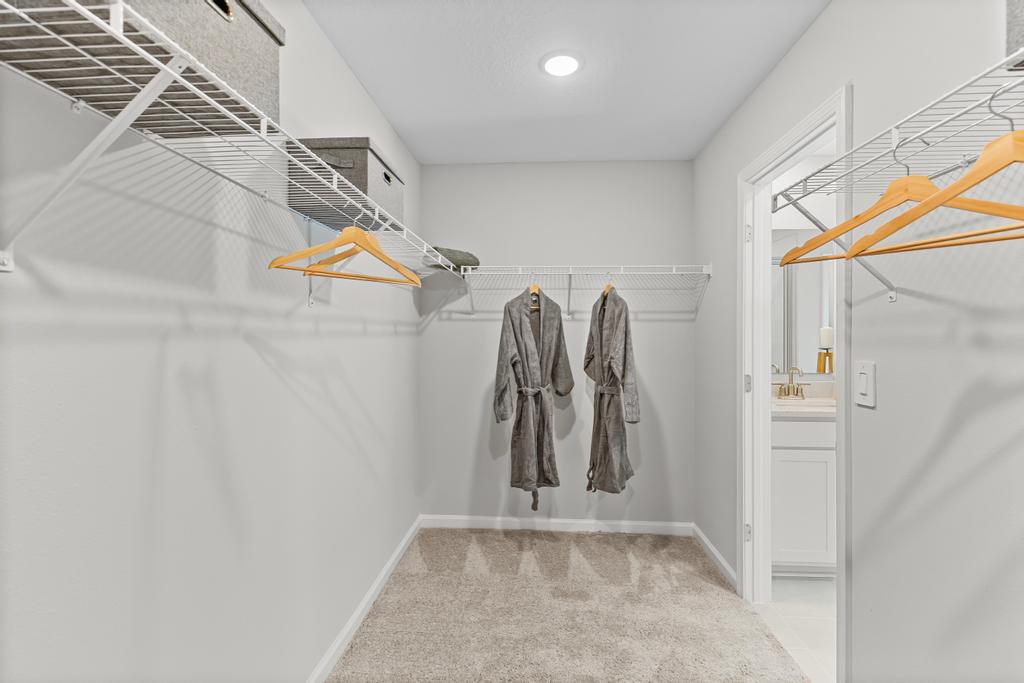 A room with a staircase and clothes on the wall.