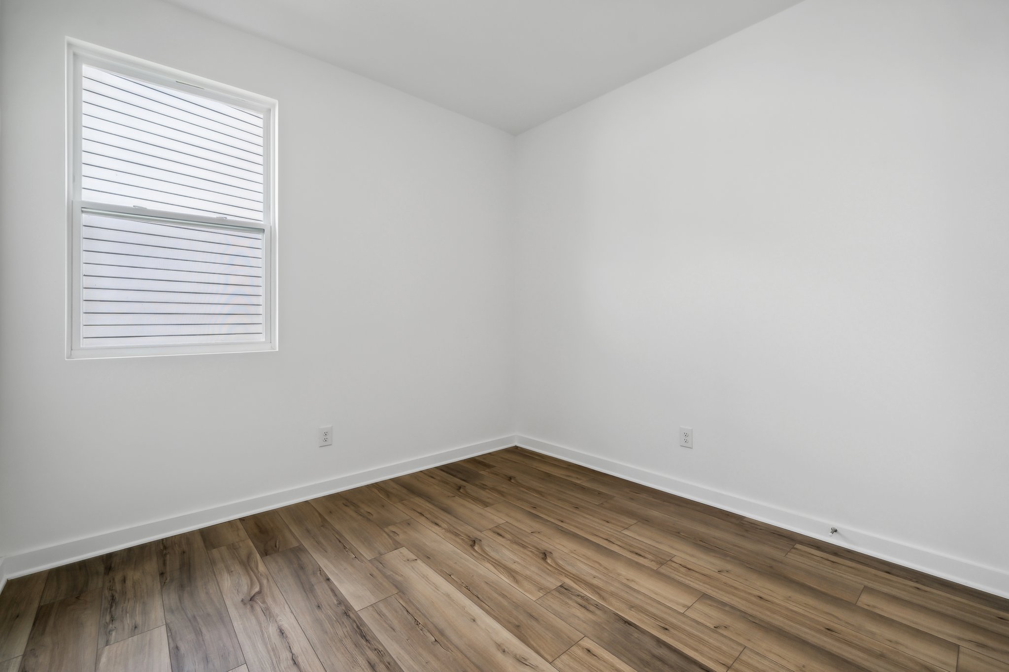 A room with a wood floor and a window.