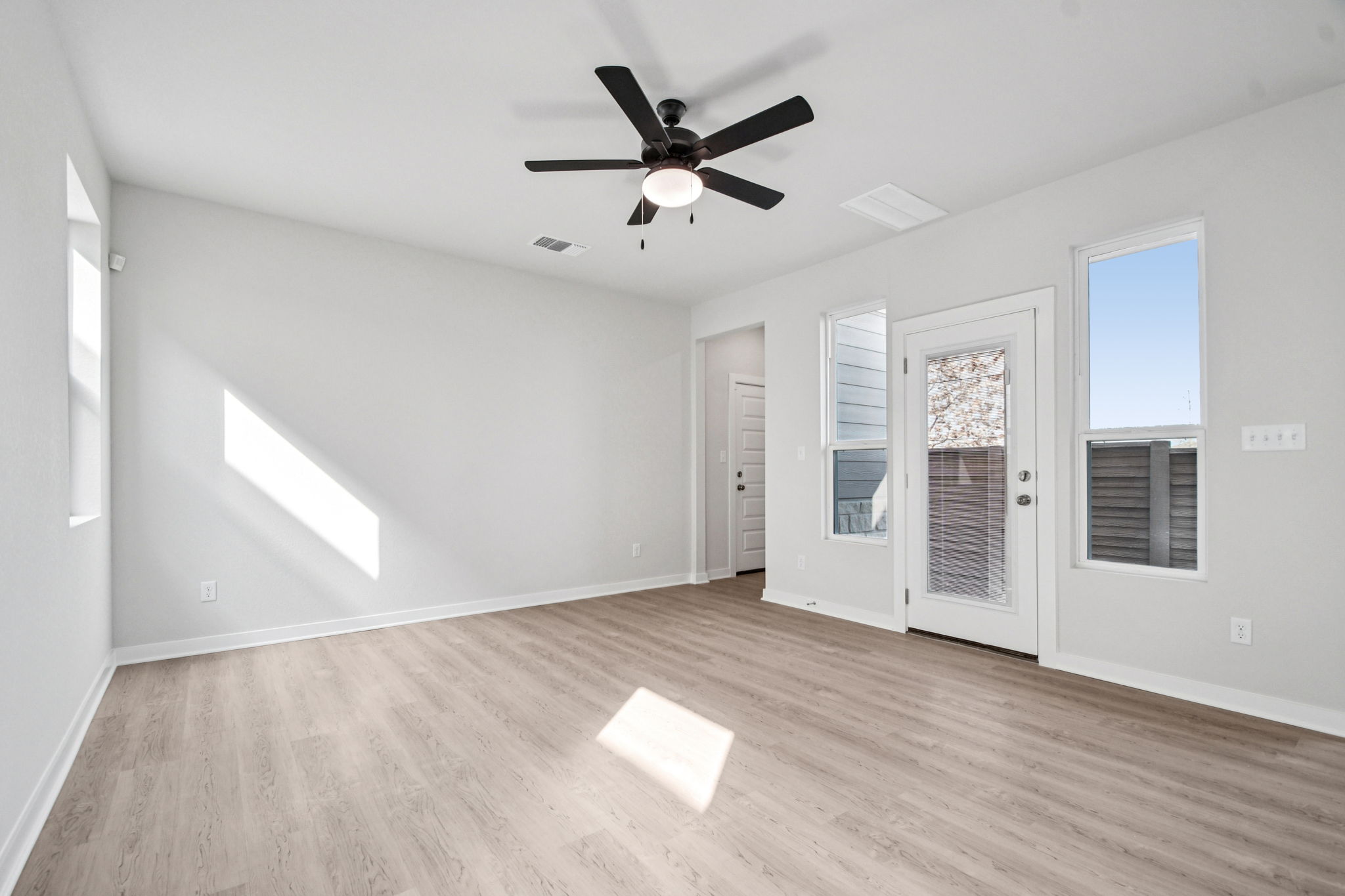 A room with a ceiling fan and a wood floor.