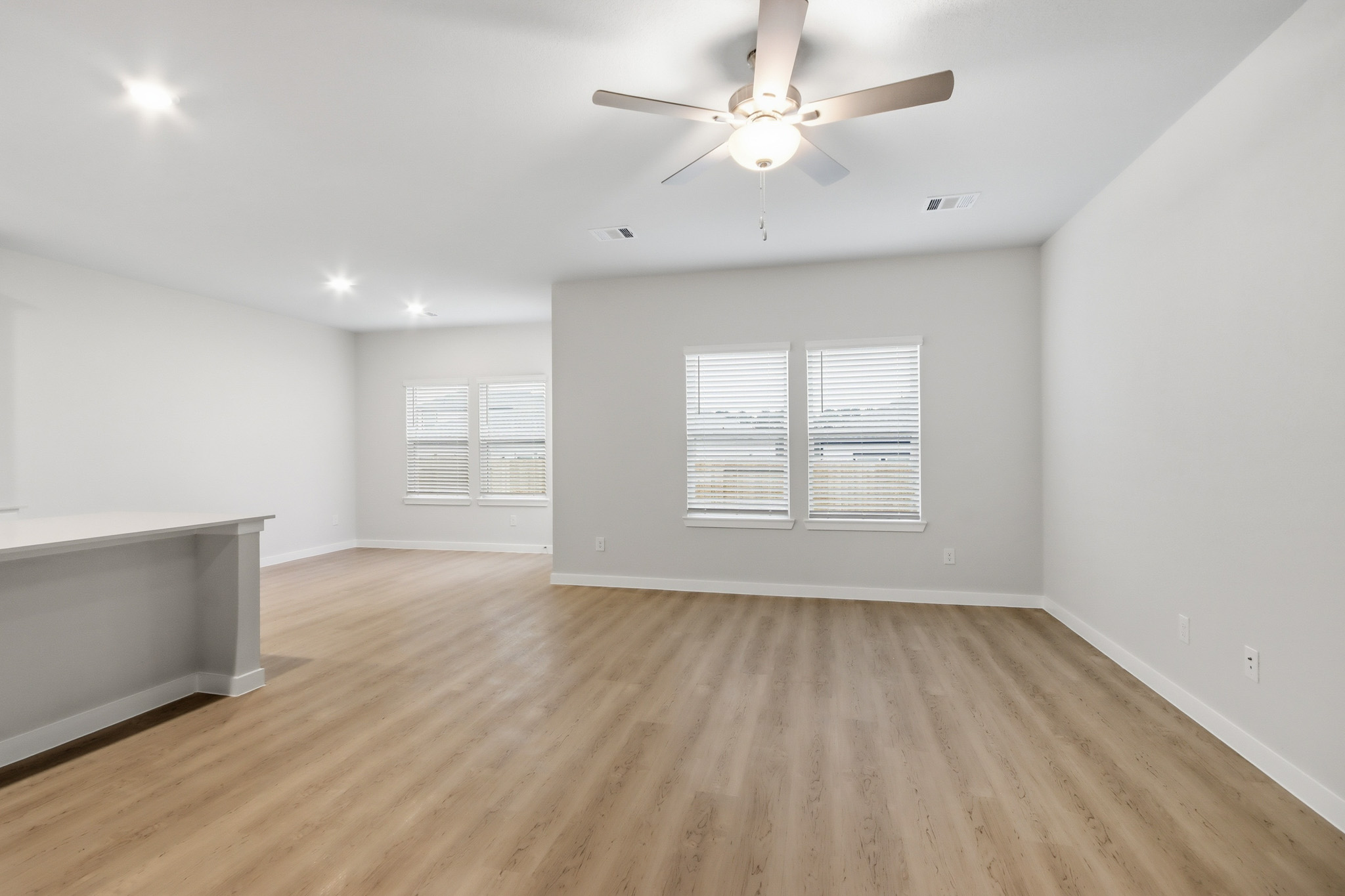A room with a ceiling fan and a wood floor.