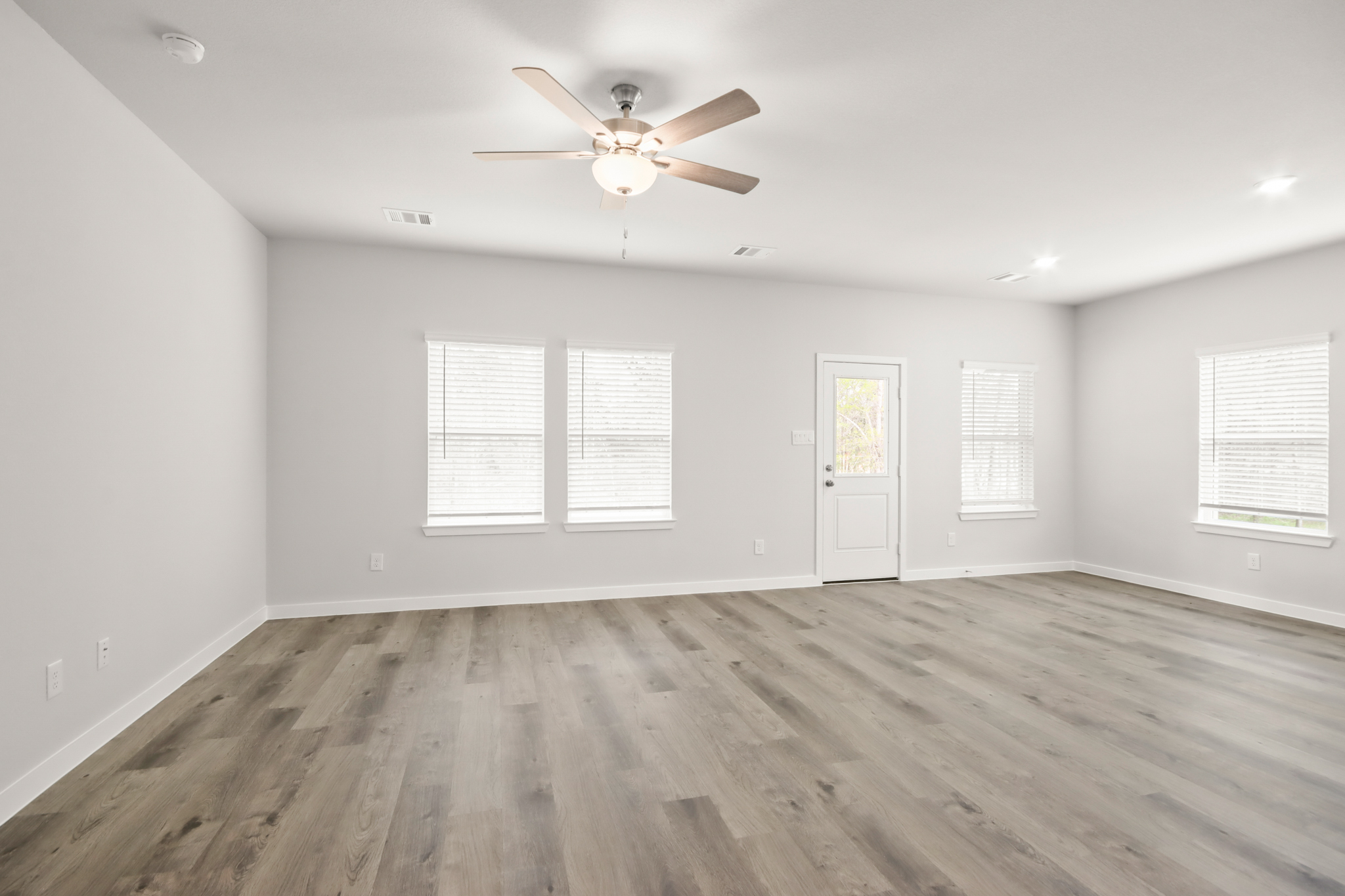 A room with a ceiling fan and a wood floor.