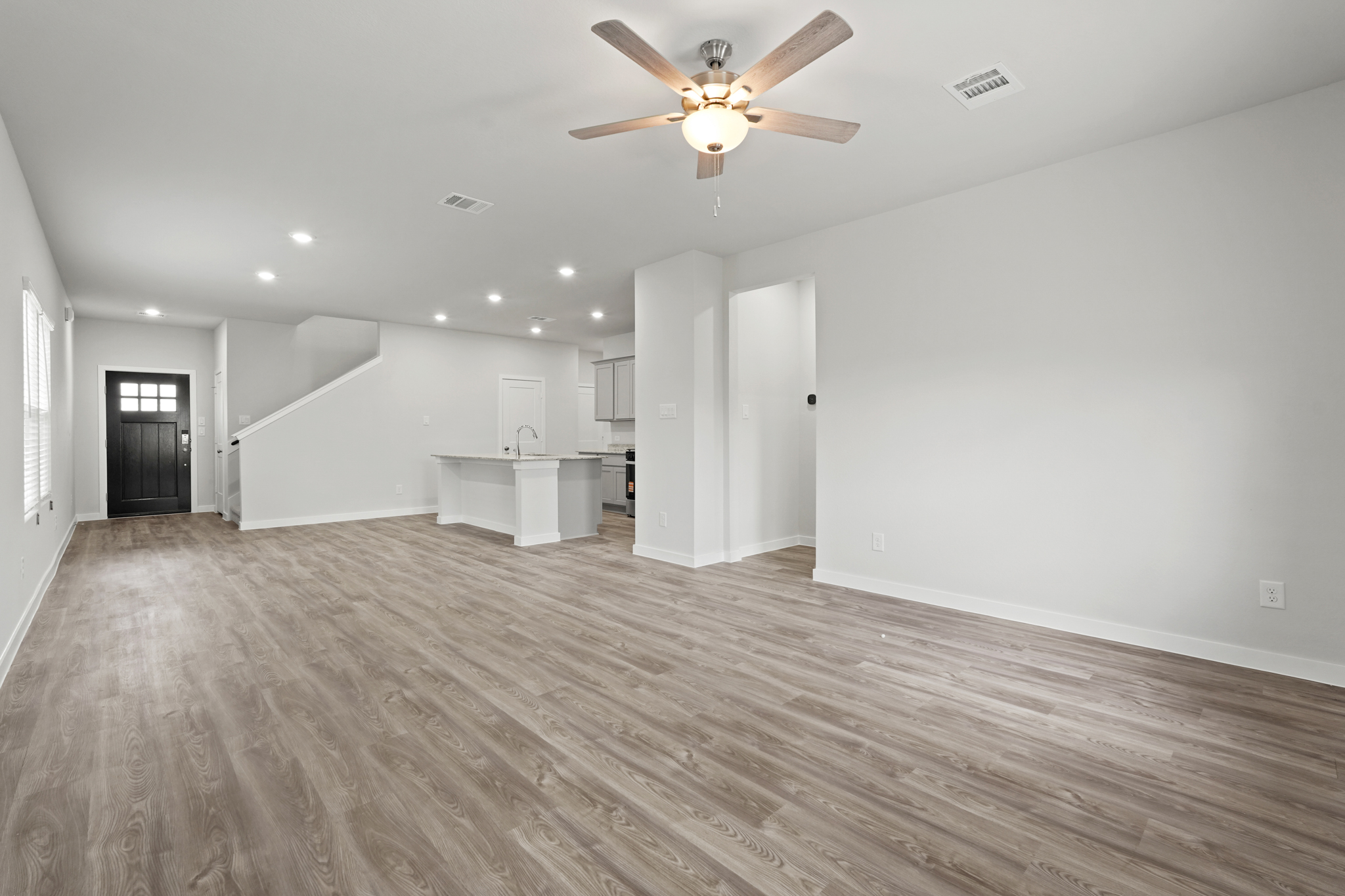 A large empty room with a ceiling fan and a wood floor.