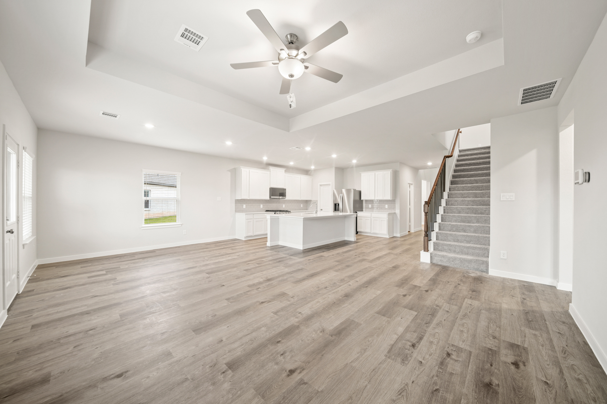 A large empty room with a wood floor and a ceiling fan.