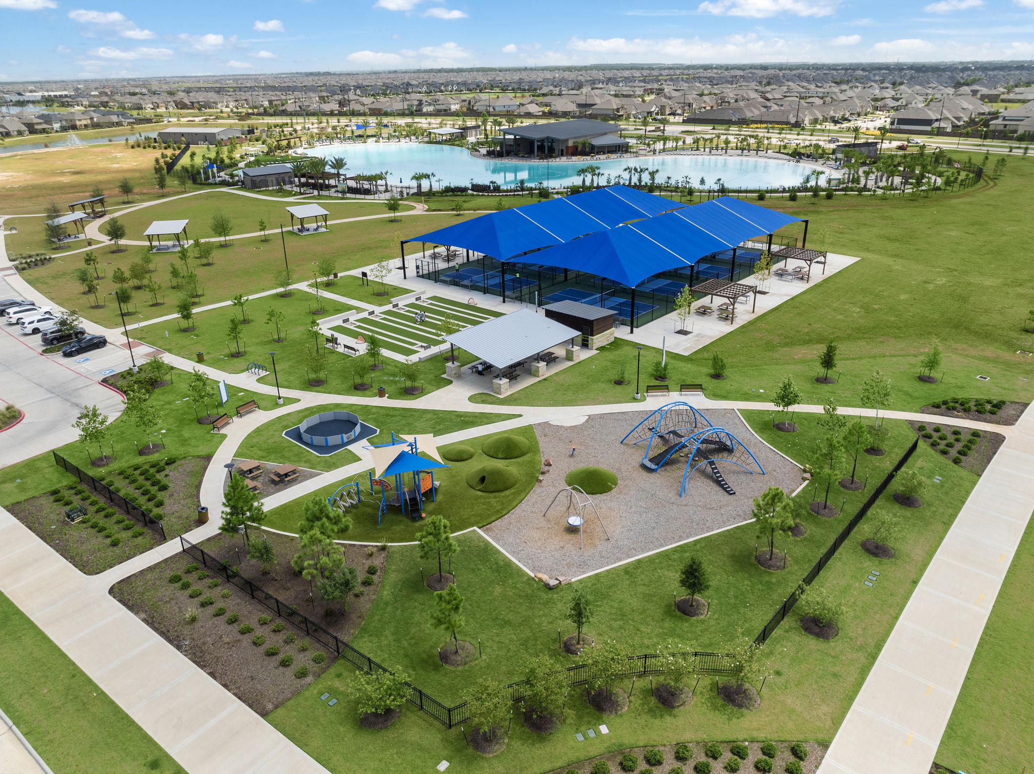 A large green field with a swimming pool and a building with a blue roof.