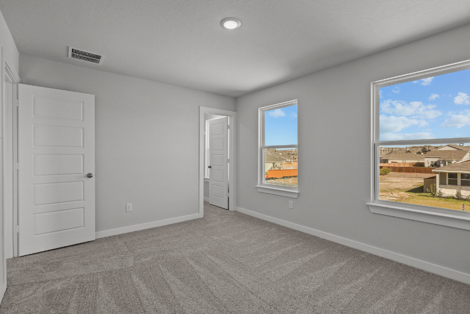 A room with white walls and a window with a view of the city.