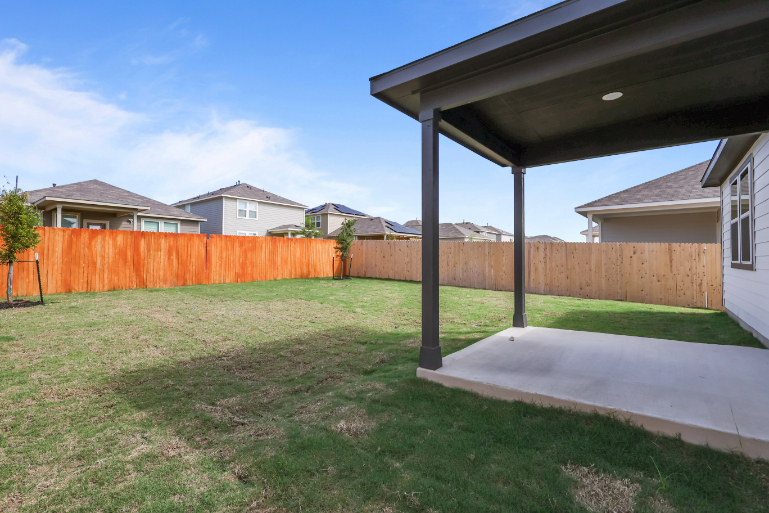 A backyard with a fence and a house.