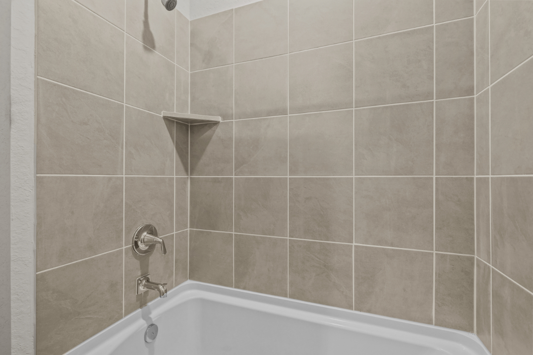 A bathtub with a tile wall.