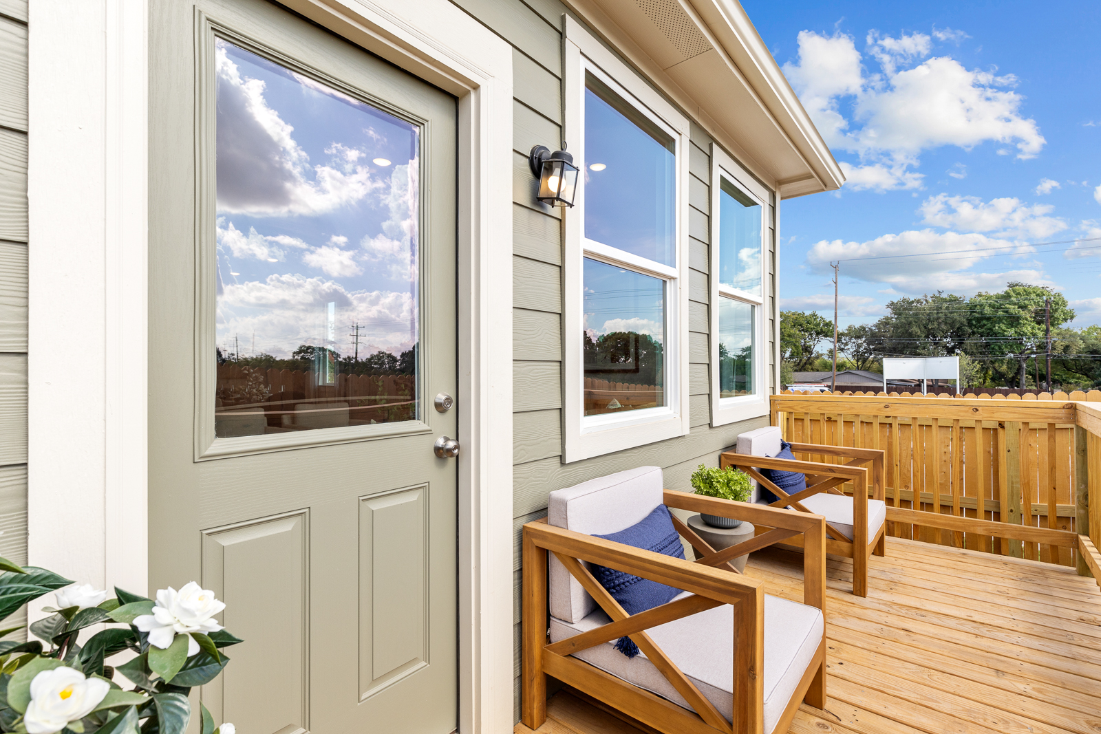 A deck with a table and chairs and a window with a view of the ocean.