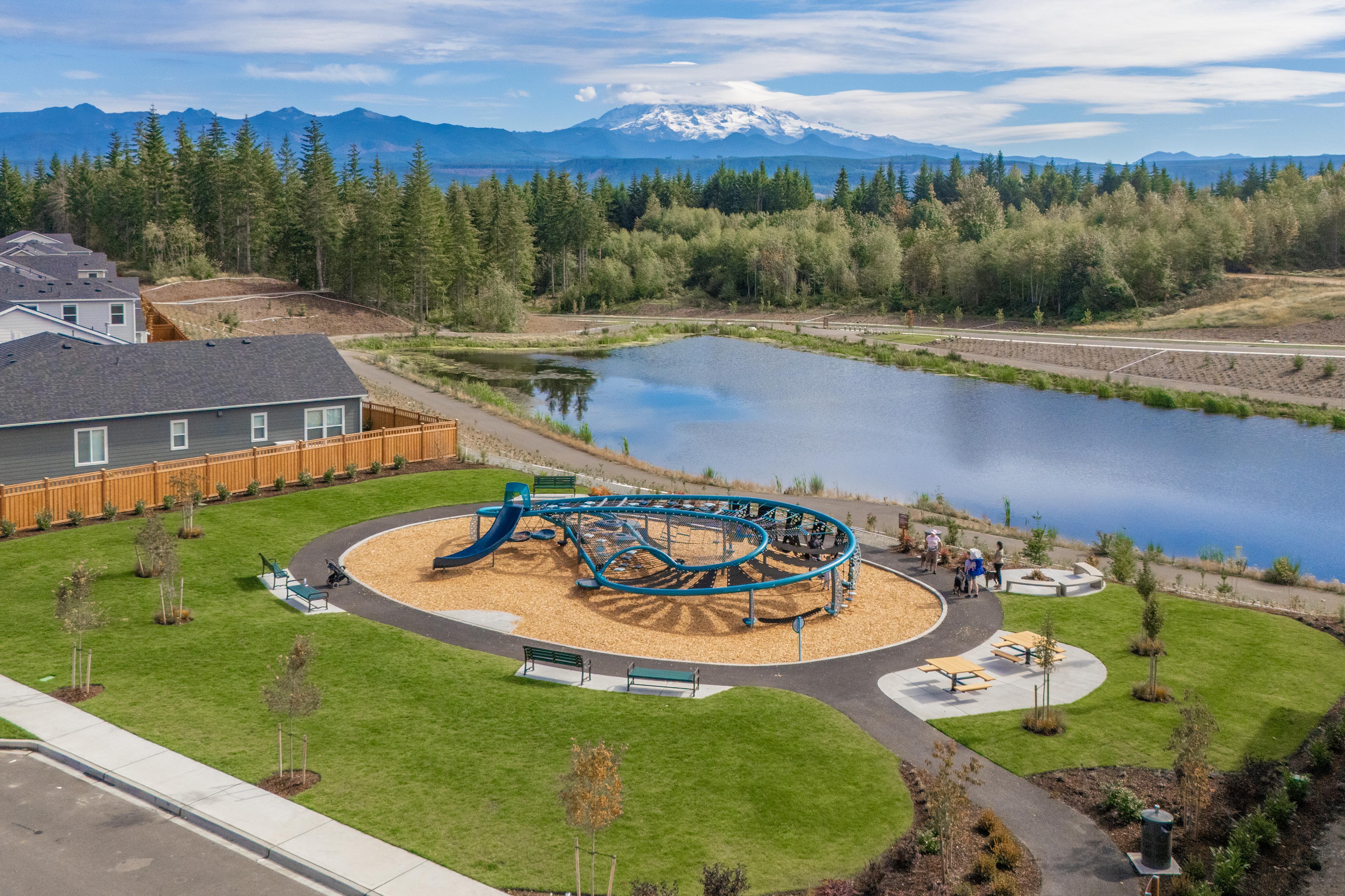 A large green landscape with a pool and a building with a mountain in the background.