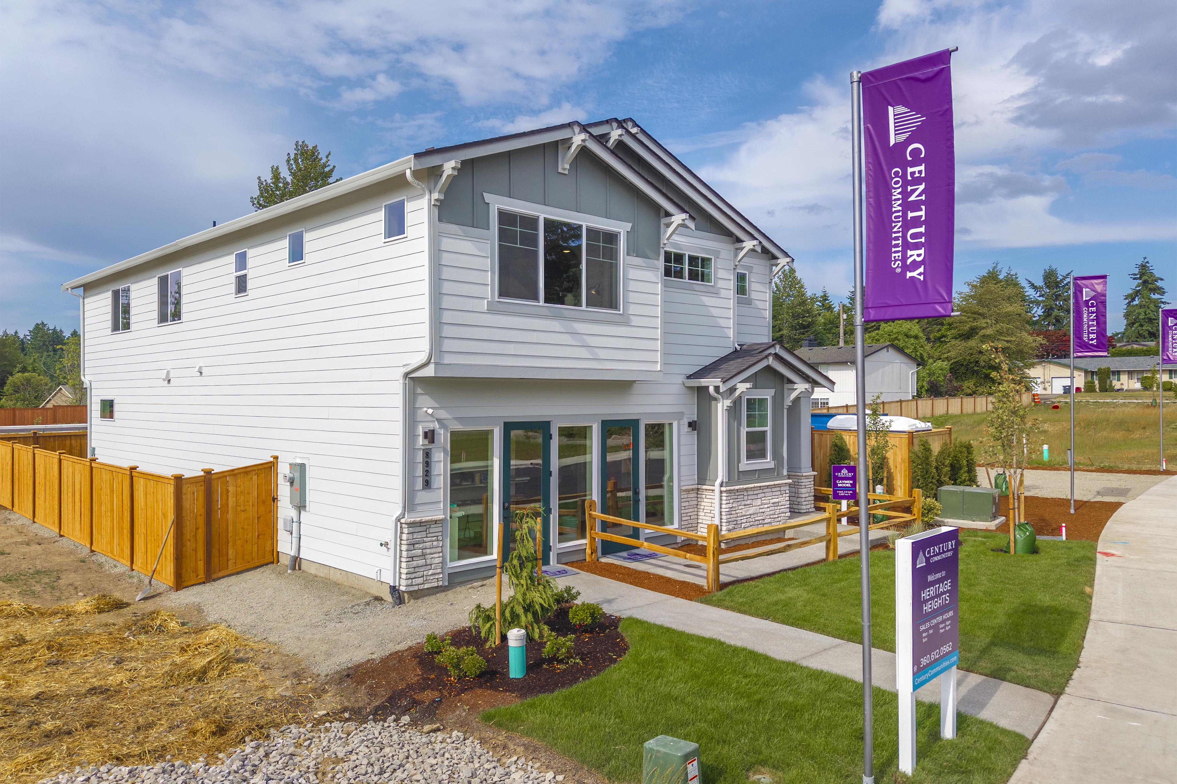 A white house with a fence and a sign in front of it.