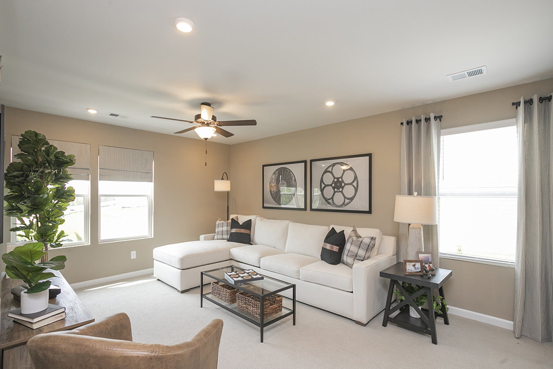 A living room with a white couch and a fan.