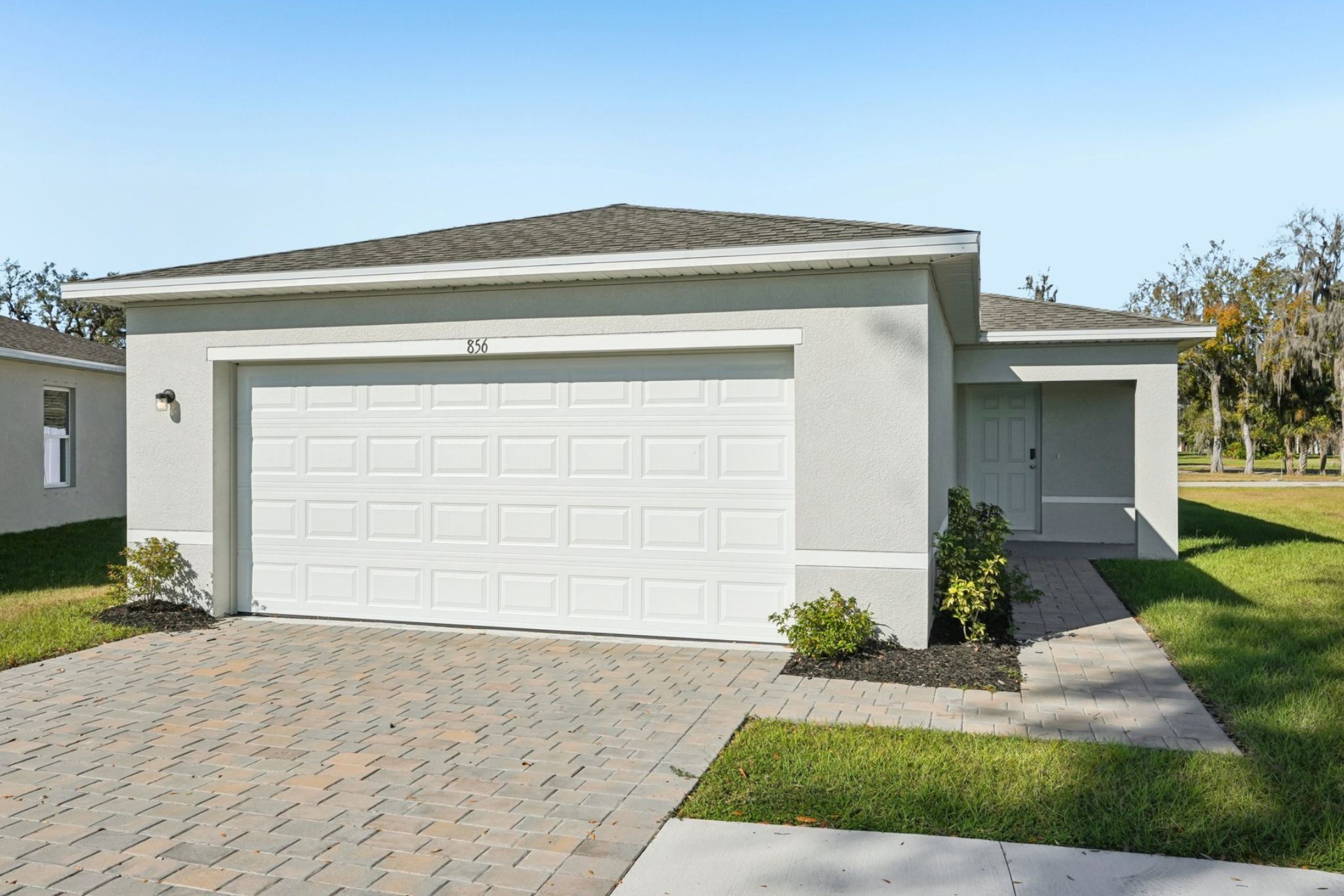 A white garage with a brick driveway.